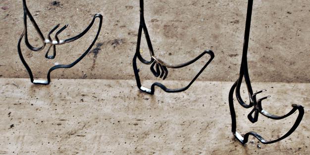 Aus Stahl geschmiedet gehen drei Schuhe so wie der Künstler Kai Althoff sie „schnürt“ hintereinander her. Kai Althoff, Löwenkäfig, Detail.  Foto: Michael Hammers Studios
